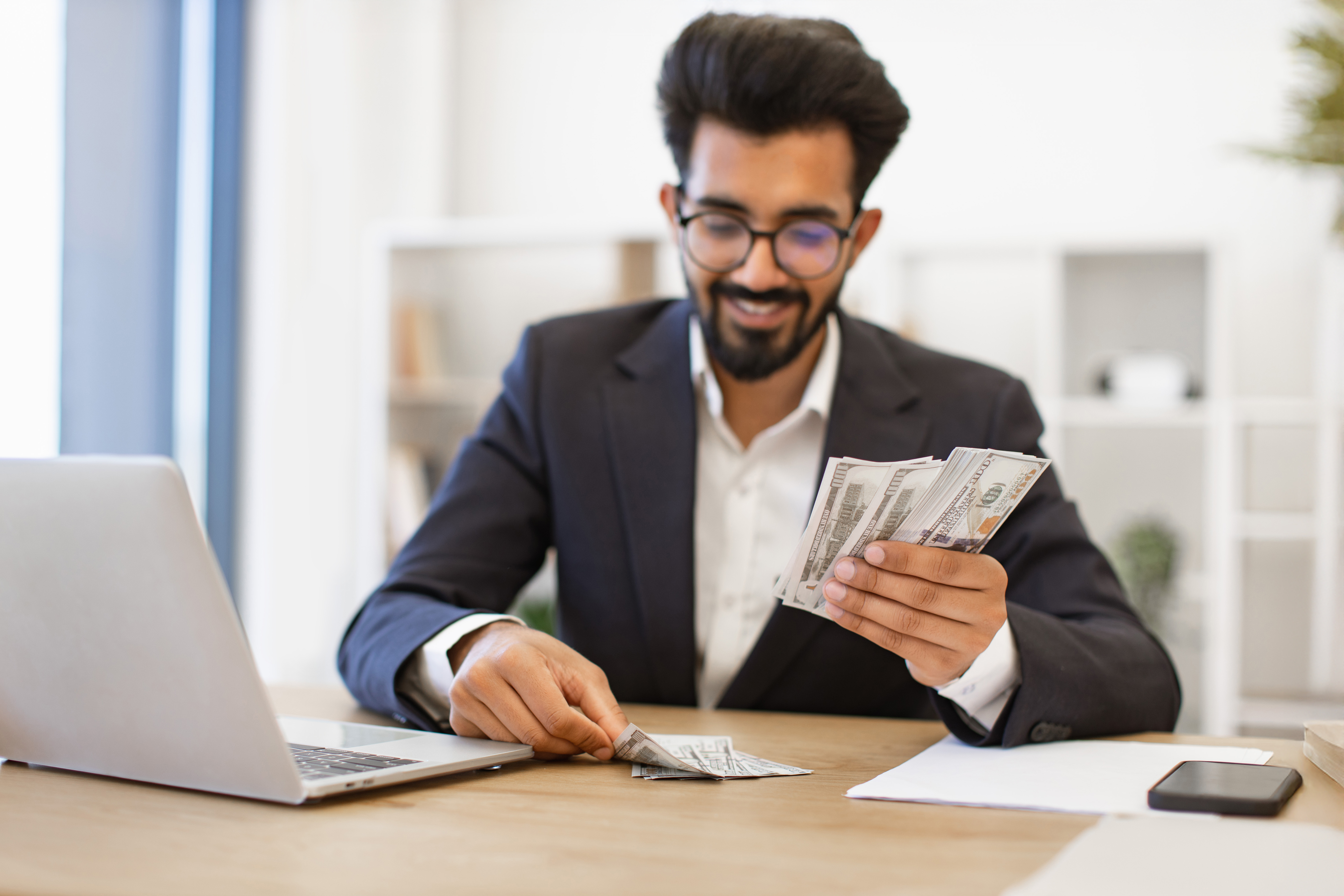 Businessman reviewing cash at desk, business loan success